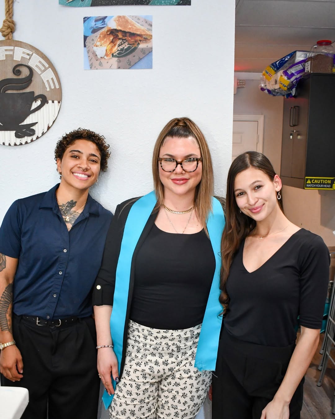 Three members of The Skinny Bean Cafe team smiling inside the shop
